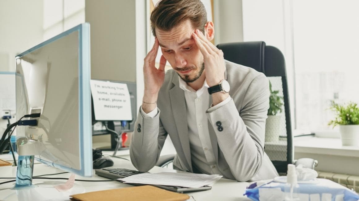 An office worker at his desk holding his head in frustration