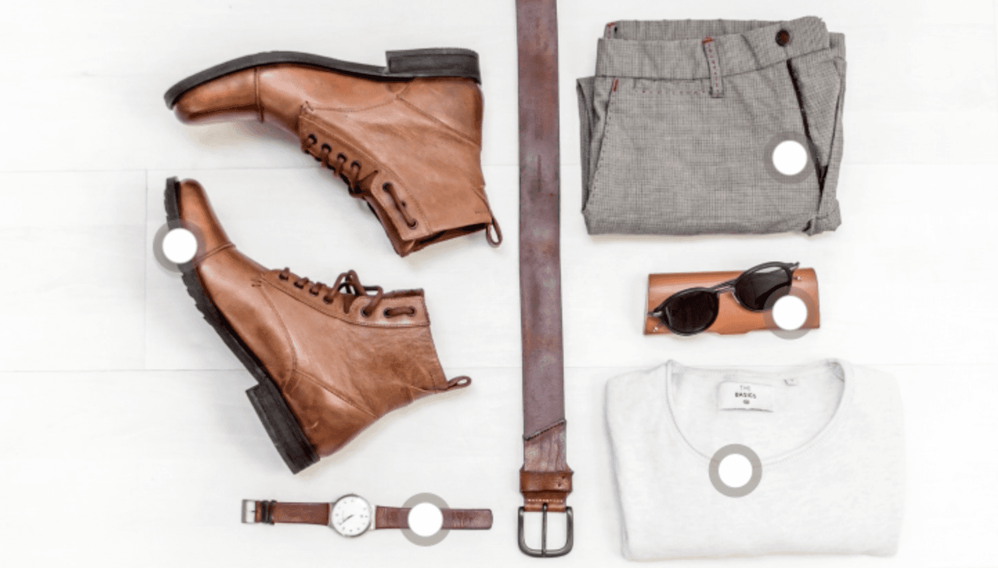 Flat-lay outfit of boots, belt, trousers, sunglasses, watch and T-shirt, each item marked with a white circular hotspot